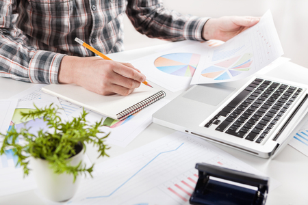 Businessman holding a pen is working with graph documents. Stock market chart and finger pointing on tablet in office.の写真素材
