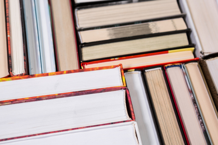 Pile of various books on bright wooden background. With copy space for your textの写真素材