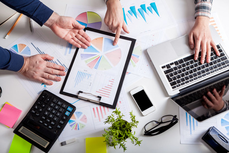 Business people discussing the charts and graphs showing the results of their successful teamwork.  Stock market chart and finger pointing on tablet in office.の写真素材