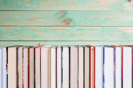 Pile of various books on bright wooden background. With copy space for your textの写真素材