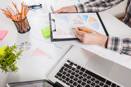Businessman holding a pen is working with graph documents. Stock market chart and finger pointing on tablet in office.の写真素材