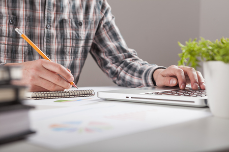 Businessman holding a pen is working with graph documents. Stock market chart and finger pointing on tablet in office.の写真素材