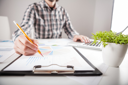 Businessman holding a pen is working with graph documents. Stock market chart and finger pointing on tablet in office.の写真素材