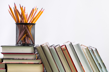 Set of pencils and pile of various books on wooden background. With copy space for your textの写真素材