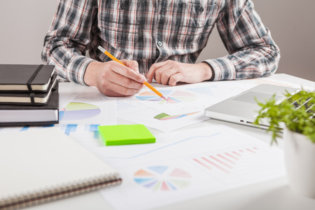 Businessman holding a pen is working with graph documents. Stock market chart and finger pointing on tablet in office.の写真素材