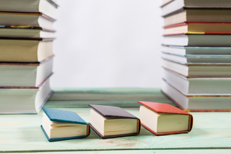 Pile of various books on bright wooden background. With copy space for your textの写真素材