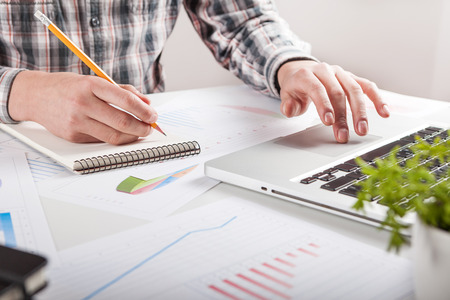 Businessman holding a pen is working with graph documents. Stock market chart and finger pointing on tablet in office.の写真素材