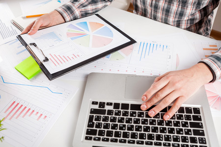 Businessman holding a pen is working with graph documents. Stock market chart and finger pointing on tablet in office.の写真素材