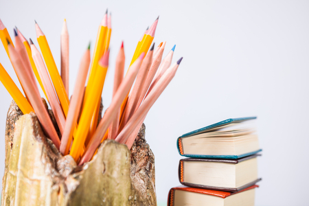 Set of pencils and pile of various books on wooden background. With copy space for your textの写真素材