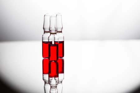Ampoules with red liquid. On white background close up. Group of ampoules with a transparent medicine in medical laboratoryの写真素材