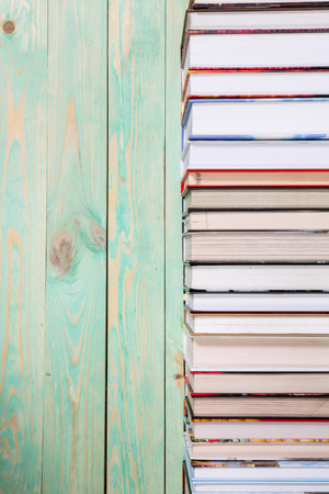 Pile of various books on bright wooden background. With copy space for your textの写真素材