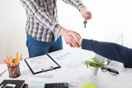 Two business person shaking hands only hands to be seen and a key is be givenの写真素材