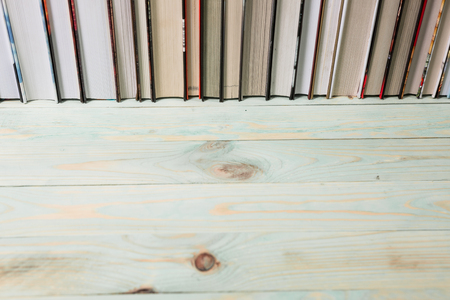 Pile of various books on bright wooden background. With copy space for your textの写真素材