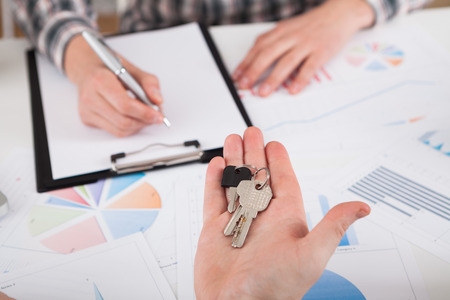 Young business man giving house with keys of customer at agency officeの写真素材