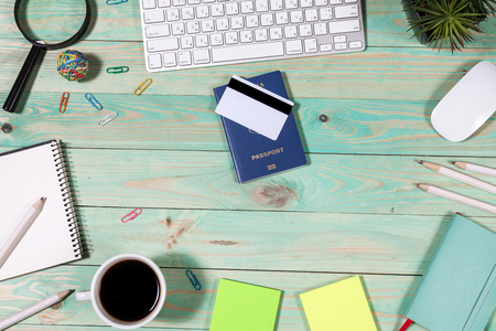 On the laptop desk foreign passport credit cards a notebook with a pen. Travel background, tourism and vacation planning, top view, copy space on white woodの写真素材