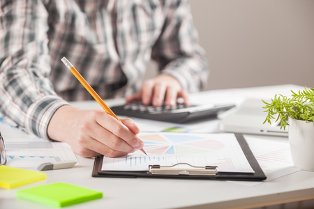 Businessman holding a pen is working with graph documents. Stock market chart and finger pointing on tablet in office.の写真素材
