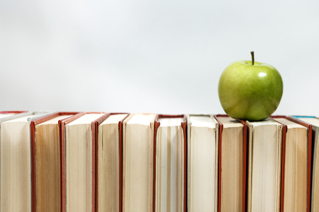 Stack of books and apple on the table. Copy space for text. Selective focus. Knowledge conceptの写真素材