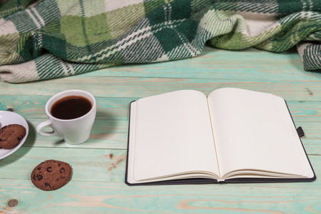 Cup with Hot Tea or Coffee, Warm Plaid, Book on a Wooden Table. with copy spaceの写真素材