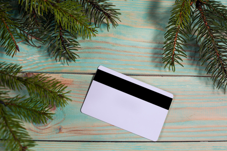 Christmas background with spruce branches and credit card on wooden board with copy space. Online shopping.の写真素材