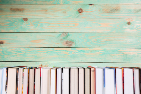 Pile of various books on bright wooden background. With copy space for your textの写真素材