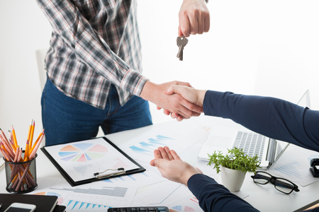 Two business person shaking hands only hands to be seen and a key is be givenの写真素材