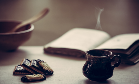 Cup of fresh coffee  with old book on wooden table. Selective focus. の写真素材