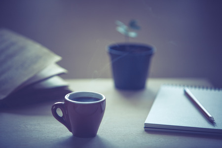Cup of fresh coffee  with old book on wooden table. Selective focus. の写真素材