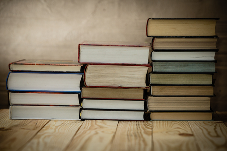 Textbooks and books on a wooden table. Book stack in the library room and blurred bookshelf for business and education background. の写真素材