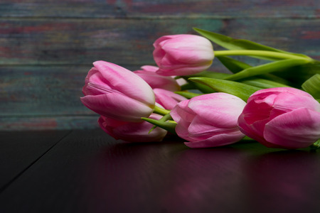 Border from bright pink tulips flowers on black wooden background.の写真素材