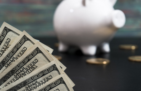 White piggy bank with one gold bitcoin coin new virtual money on a colored wooden backgroundの写真素材