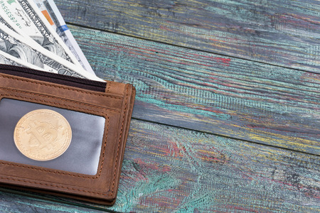 Bitcoin and money in a purse on a colored wooden background. Bitcoin golden coin New virtual moneyの写真素材