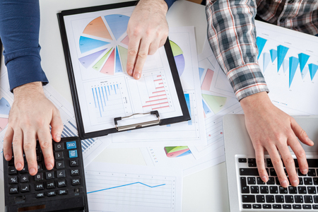 Business people discussing the charts and graphs showing the results of their successful teamwork.  Stock market chart and finger pointing on tablet in office.の写真素材