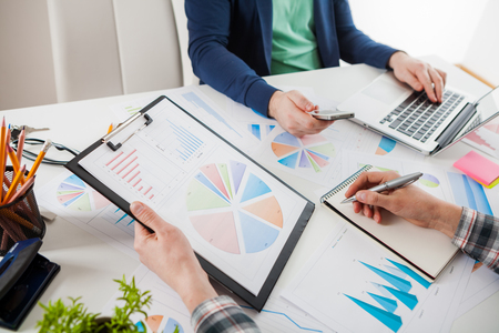 Business people discussing the charts and graphs showing the results of their successful teamwork.  Stock market chart and finger pointing on tablet in office.の写真素材