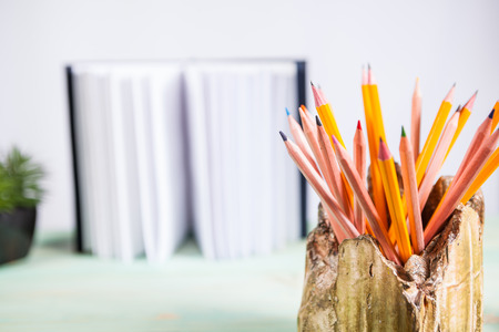 Set of pencils and pile of various books on wooden background. With copy space for your textの写真素材
