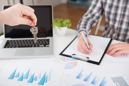 Young business man giving house with keys of customer at agency officeの写真素材