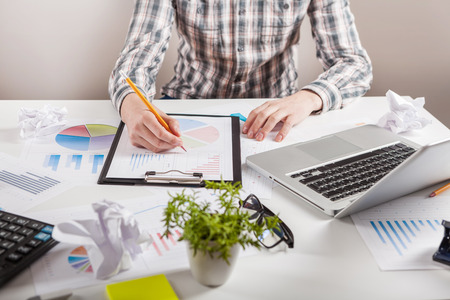 Businessman holding a pen is working with graph documents. Stock market chart and finger pointing on tablet in office.の写真素材