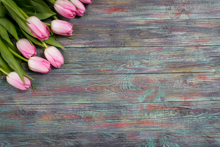 Border from bright pink tulips flowers on wooden background. Selective focus, place for textの写真素材