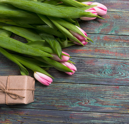 Pink tulips flowers with gift box on wooden background. Selective focus, place for textの写真素材