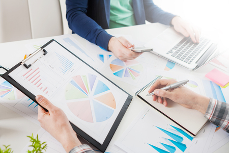 Business people discussing the charts and graphs showing the results of their successful teamwork.  Stock market chart and finger pointing on tablet in office.の写真素材