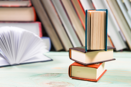 Open book and pile of various books on wooden background. With copy space for your textの写真素材