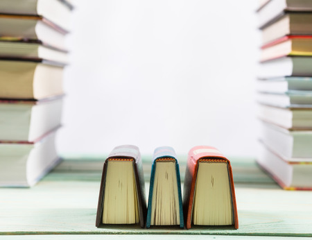 Pile of various books on bright wooden background. With copy space for your textの写真素材
