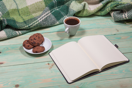 Cup with Hot Tea or Coffee, Warm Plaid, Book on a Wooden Table. with copy spaceの写真素材