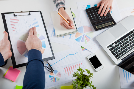 Business people discussing the charts and graphs showing the results of their successful teamwork.  Stock market chart and finger pointing on tablet in office.の写真素材