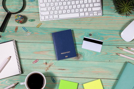 On the laptop desk foreign passport credit cards a notebook with a pen. Travel background, tourism and vacation planning, top view, copy space on white woodの写真素材