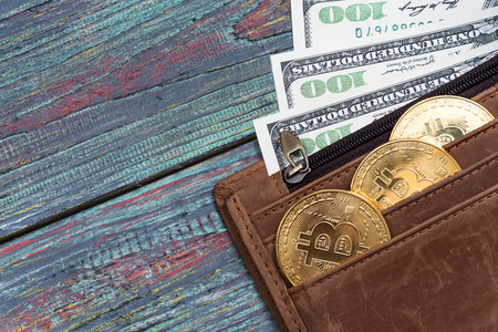 Bitcoin and money in a purse on a colored wooden background. Bitcoin golden coin New virtual moneyの写真素材