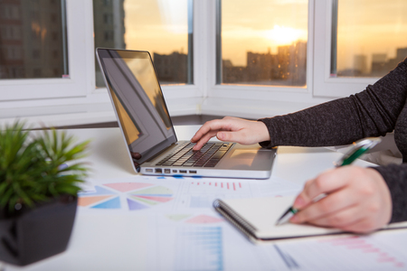 Business women work process. Marketing strategy brainstorming. Paperwork and digital in office. The windows are sunset.の写真素材