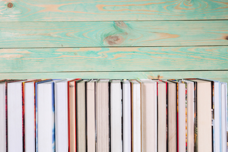 Pile of various books on bright wooden background. With copy space for your textの写真素材
