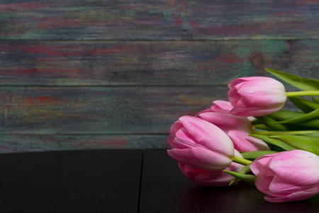 Border from bright pink tulips flowers on black wooden background. Selective focus. Place for text. Flat lay.の写真素材