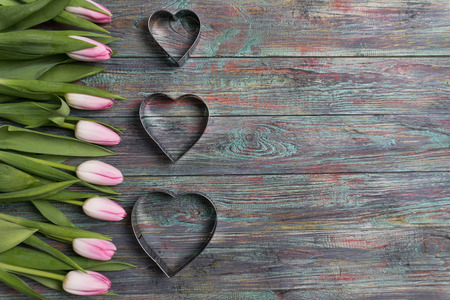 Pink tulips flowers with a metallic heart image on wooden background. Selective focus, place for textの写真素材