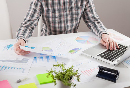 Businessman holding a pen is working with graph documents. Stock market chart and finger pointing on tablet in office.の写真素材